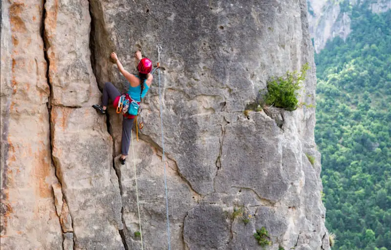 woman with red helmet climbing with half ropes