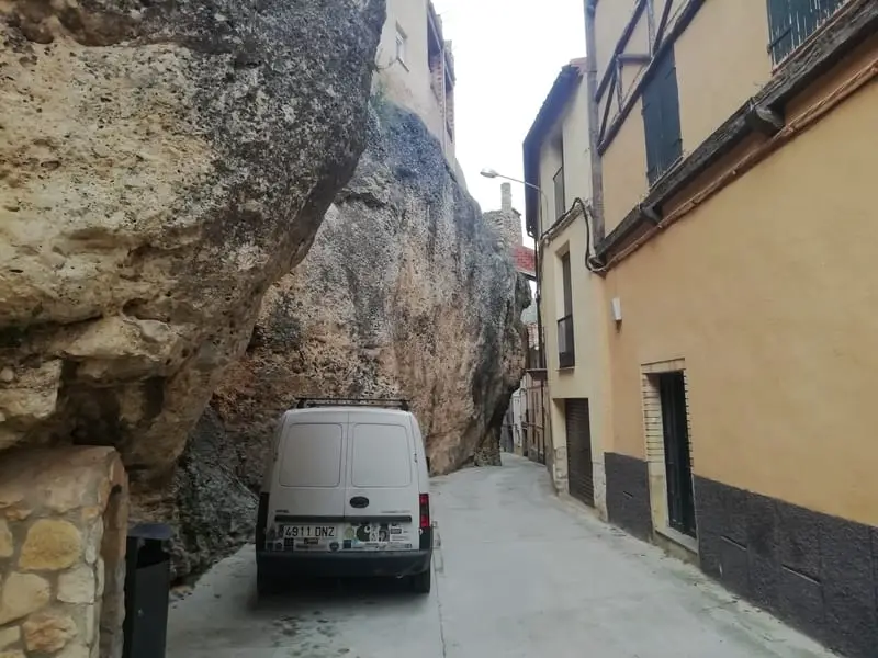 van parked in the streets of margalef spain with rocks hanging over