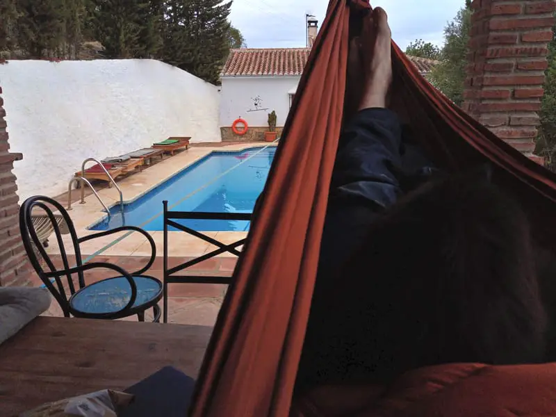 person relaxing in hammock with pool