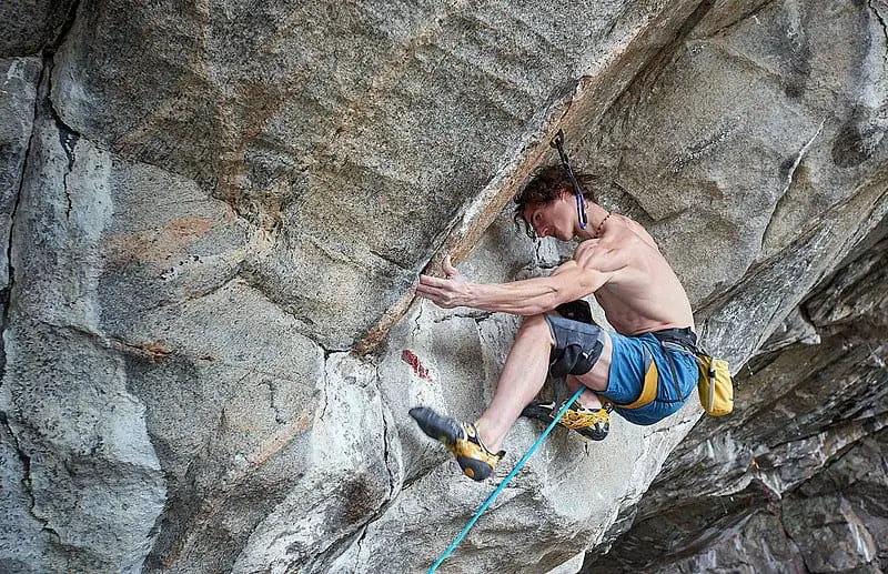 man rock climbing with arm outstretched
