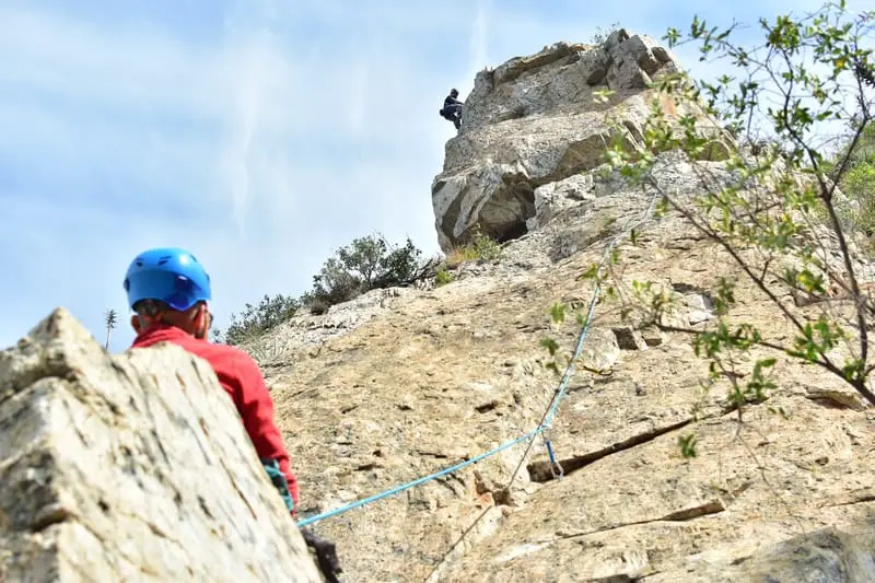 mean lead climbing with belayer in foreground looking up
