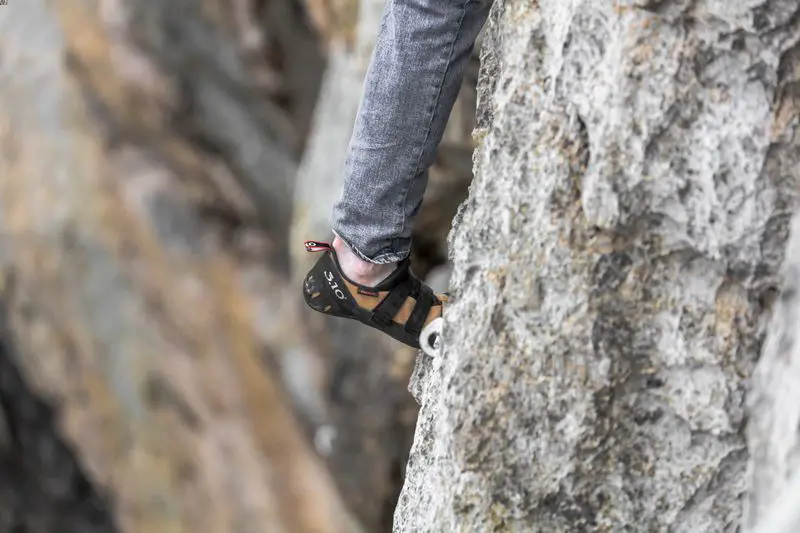 Person climbing rock, focus on shoes