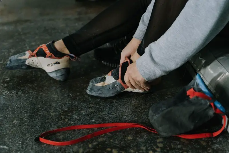 women putting on aggressive downturned climbing shoes