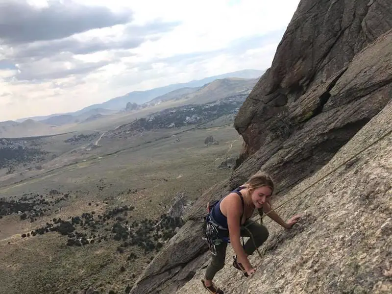 Woman climbing rock overlooking mountains 