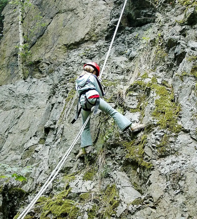 Boy in harness climbing rocks descending