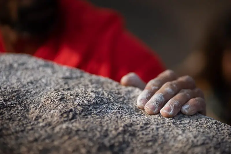 Man climbing rock with chalk on hands