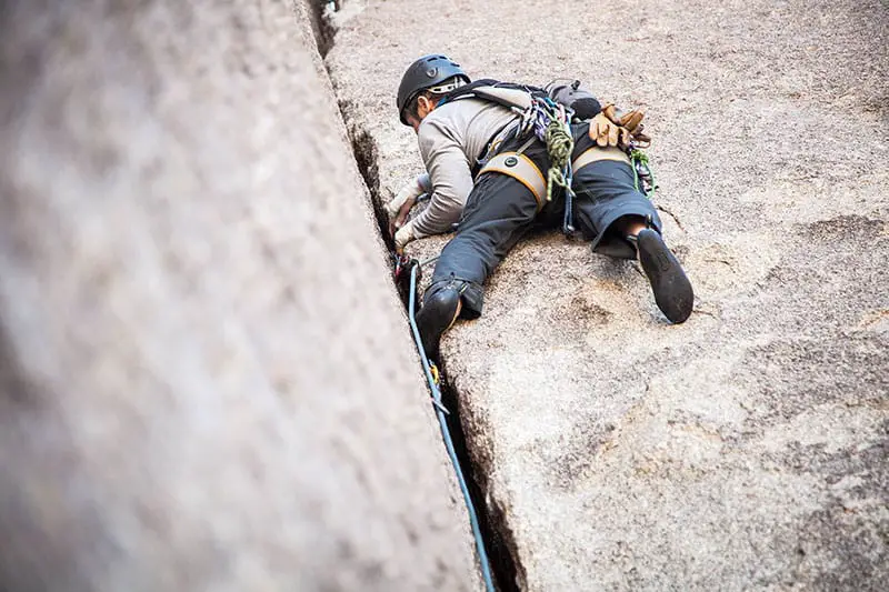 man climbing rock crack view