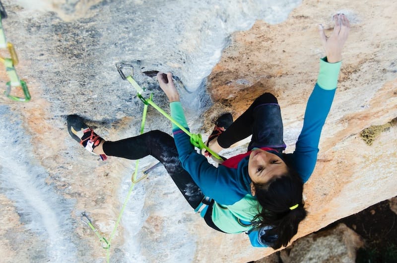 woman climbing a tufa route with bright green rope