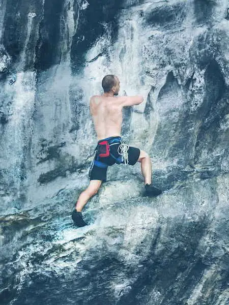 man climbing waterfall